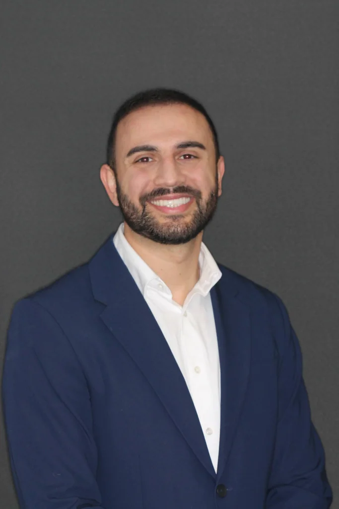 Dr. Broneil Ishaya, DDS, smiling in a navy blazer and white shirt